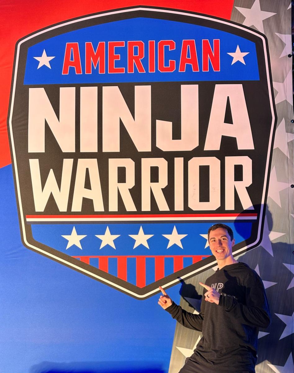 Nate Person pointing to American Ninja Warrior sign