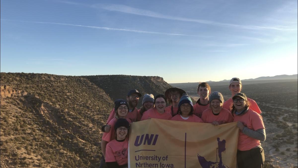 11 UNI students holding up UNI flag on Adventure Trip