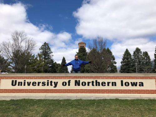 Bob Dorr on UNI campus behind University of Northern Iowa sign, in front of the Campanile