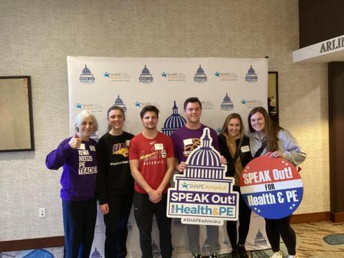 UNI students posing in front of a photo backdrop for SPEAK Out! Day