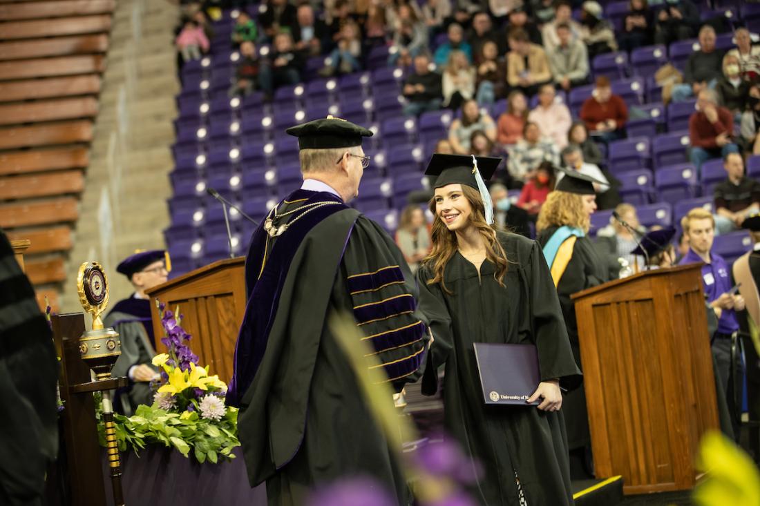 Student walking across stage at college graduation ceremony