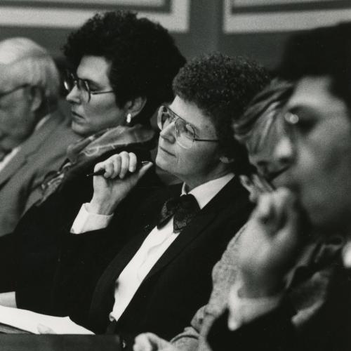 Patricia Geadelmann sitting at a table, holding a pen in 1988.