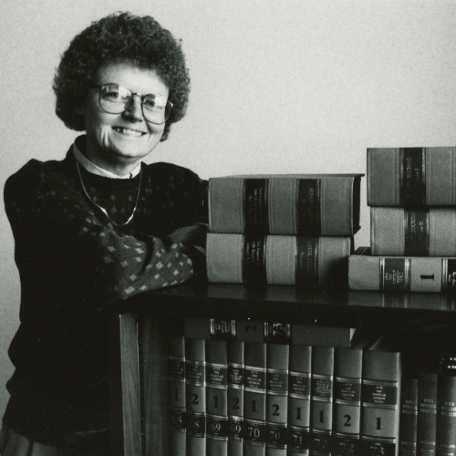Patricia Geadelmann posing by a shelf of books in 1990.