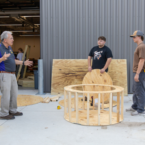 Students and faculty assemble wooden cake for UNI Homecoming float