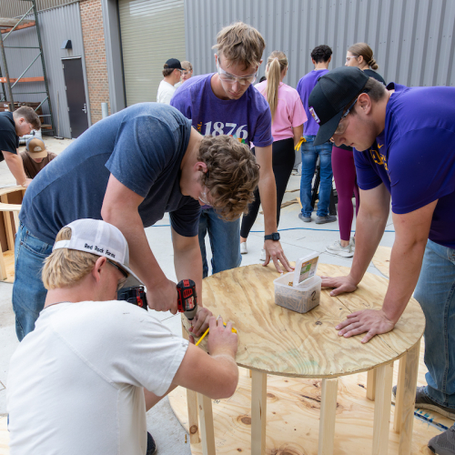 Students assembling wooden cake for UNI Homecoming float
