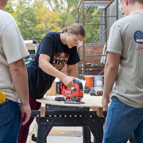 Student sawing wood for UNI Homecoming float