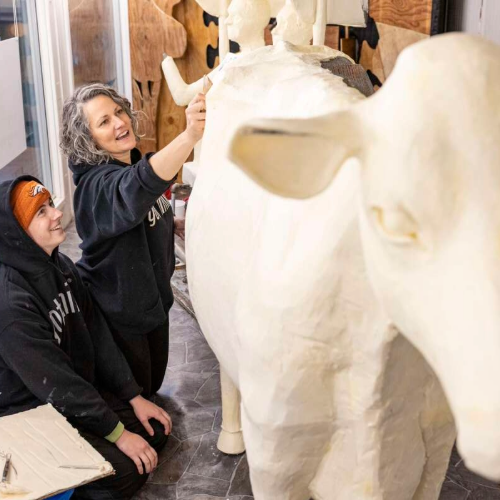 Sarah and Grace Pratt sculpting the butter cow. 
