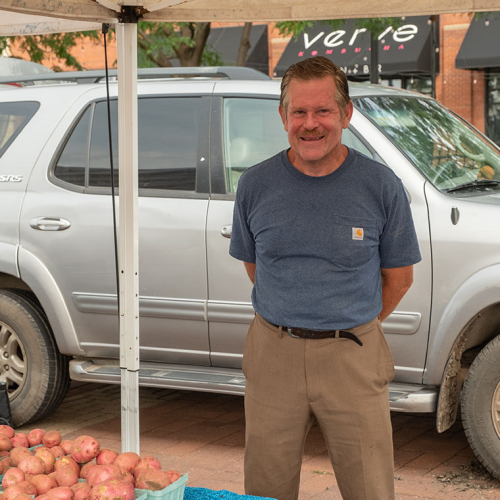 Man smiling at the camera in front of a truck.