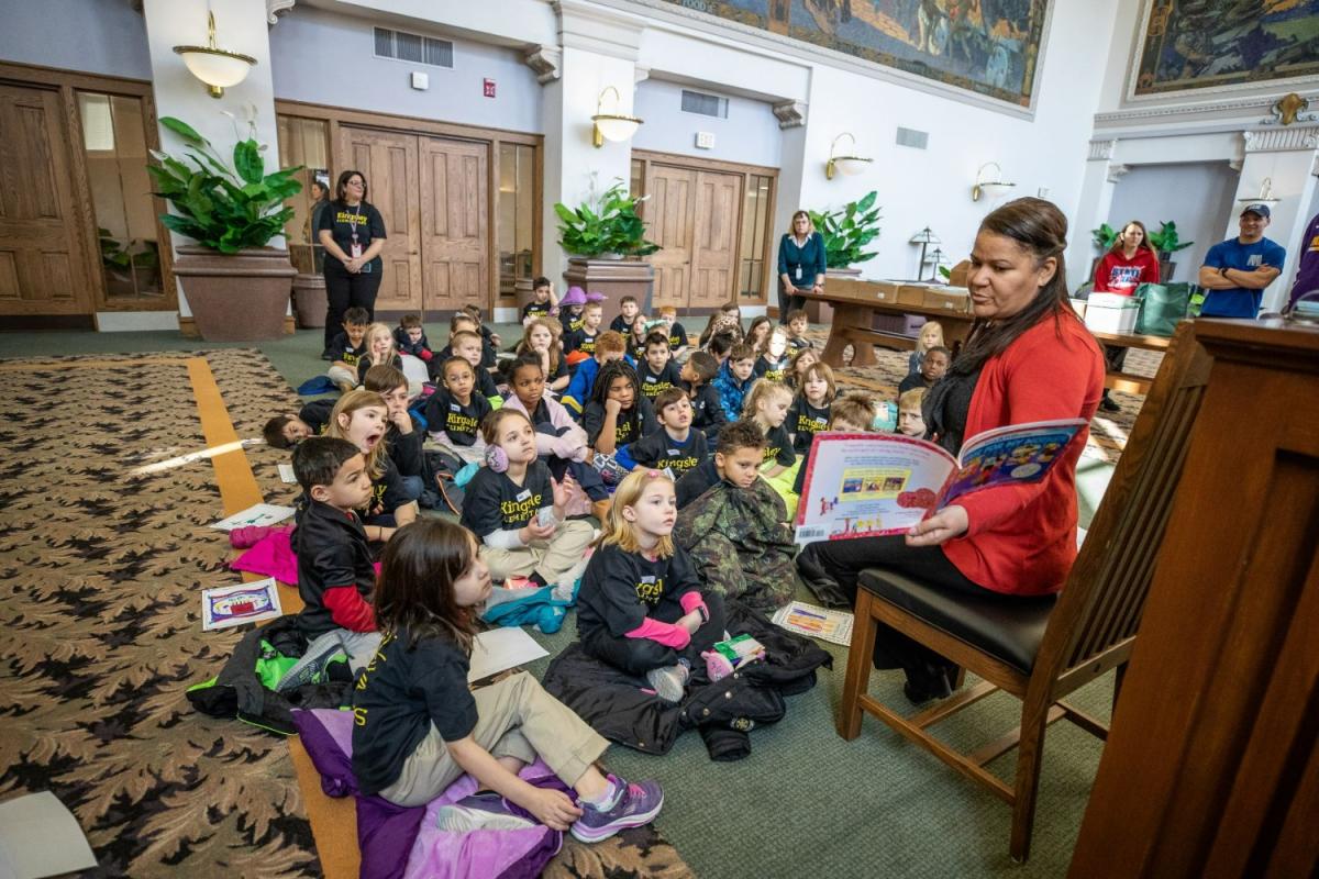 Woman reading a book to a group of children