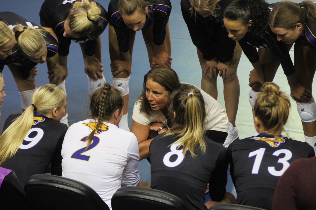 Bobbi Petersen talking to volleyball players in a huddle