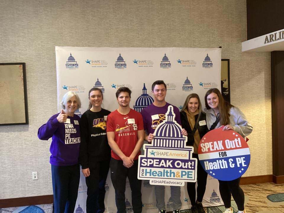 UNI students posing in front of photo backdrop for SPEAK Out! Day