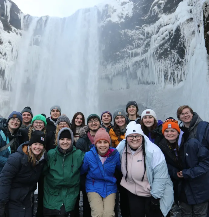 Students standing in front of a white frozen waterfall