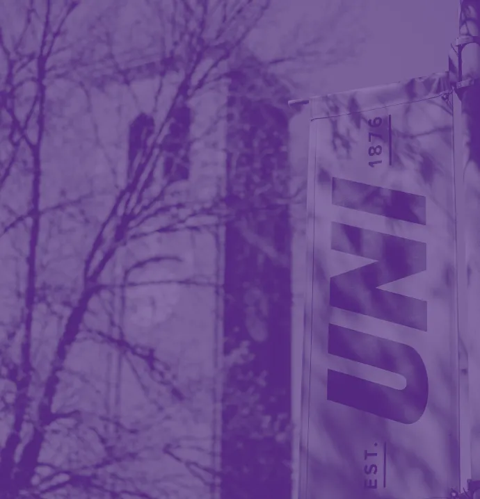 Purple-tinted photo of a UNI banner reading “UNI Est. 1876,” with the UNI Campanile building visible in the background among trees.