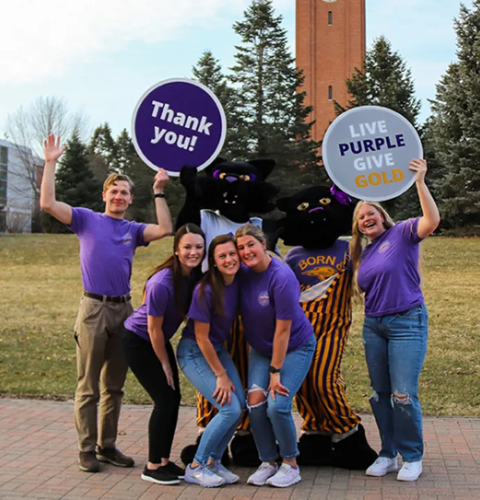 UNI students wearing Live Purple Give Gold shirts posing with TK and TC with thank you signs