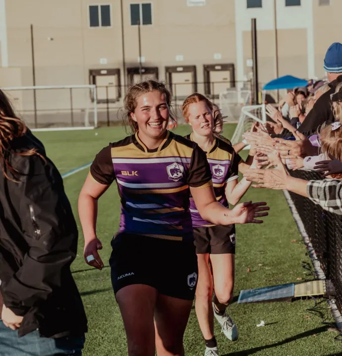 UNI women's rugby high-fiving crowd
