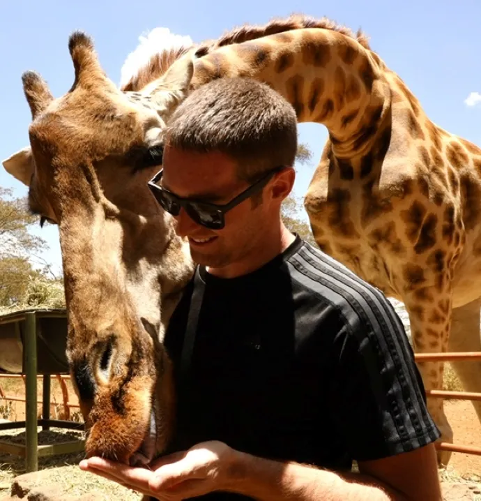Brett Meehan feeding a giraffe from the palm of his hand