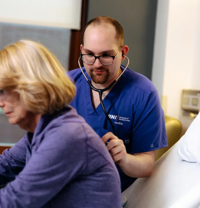 Nursing student using stethoscope on patient