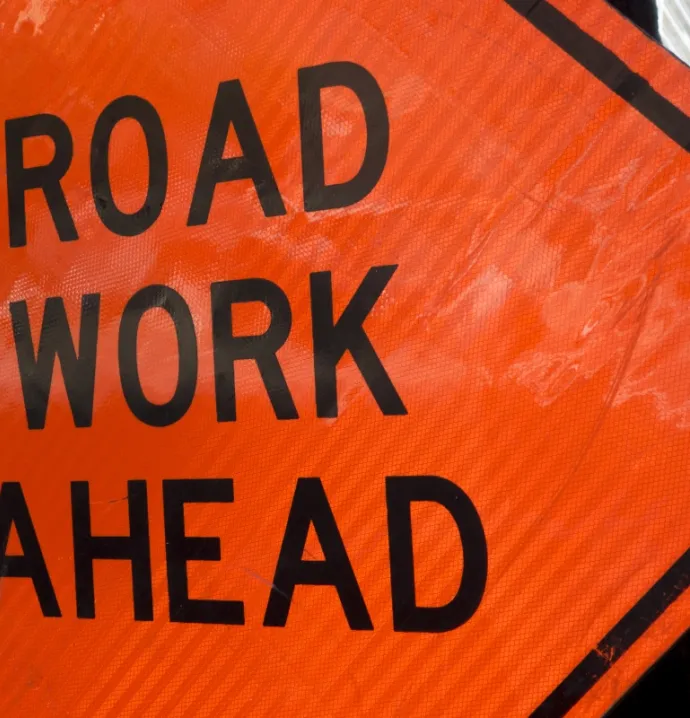 A sign signals road construction on a city street