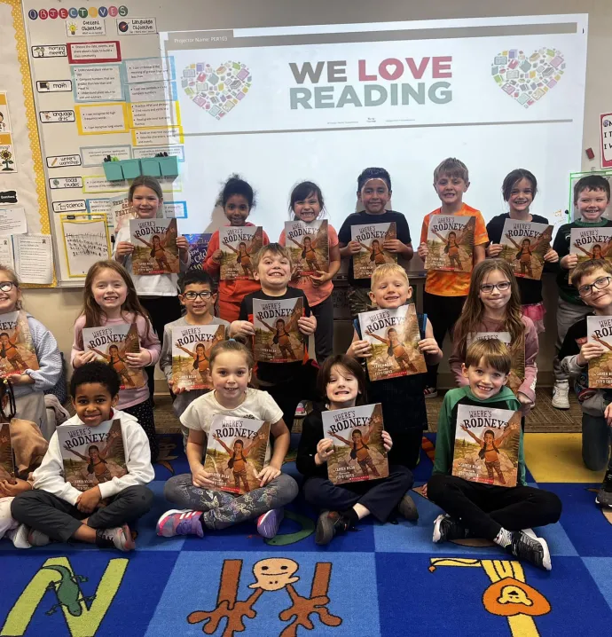 Students holding up "Where's Rodney?" book for African American Read-In