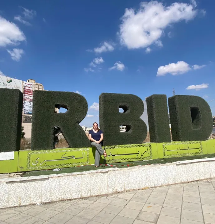 Elizabeth Rench in front of sign that says Irbid