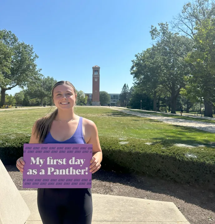 Lucy Gipple holding "My first day as a Panther" sign on UNI campus
