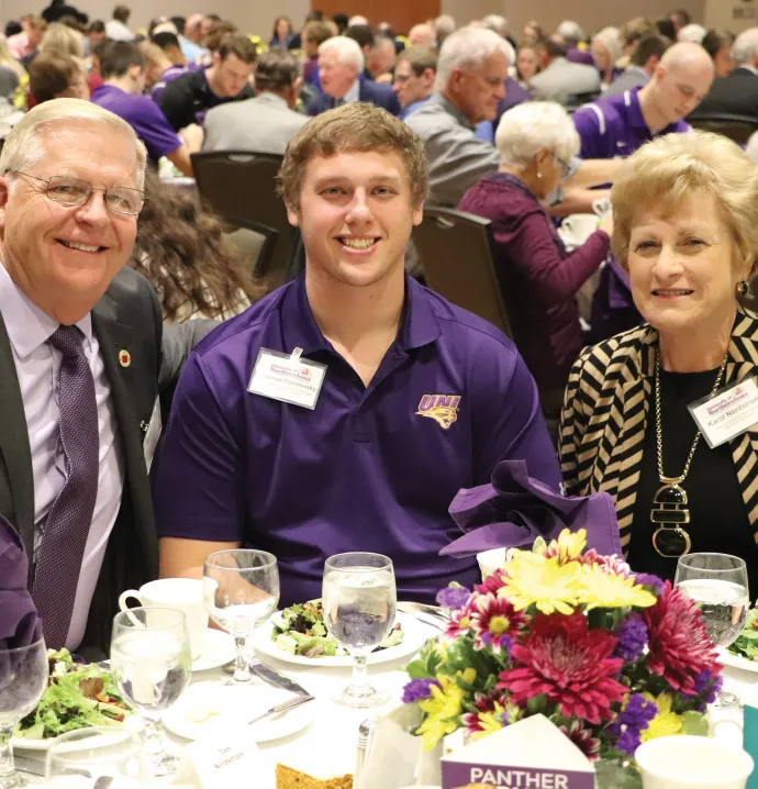 Tom and Karol Nordstrom sit with a UNI student at the UNI Scholarship Luncheon