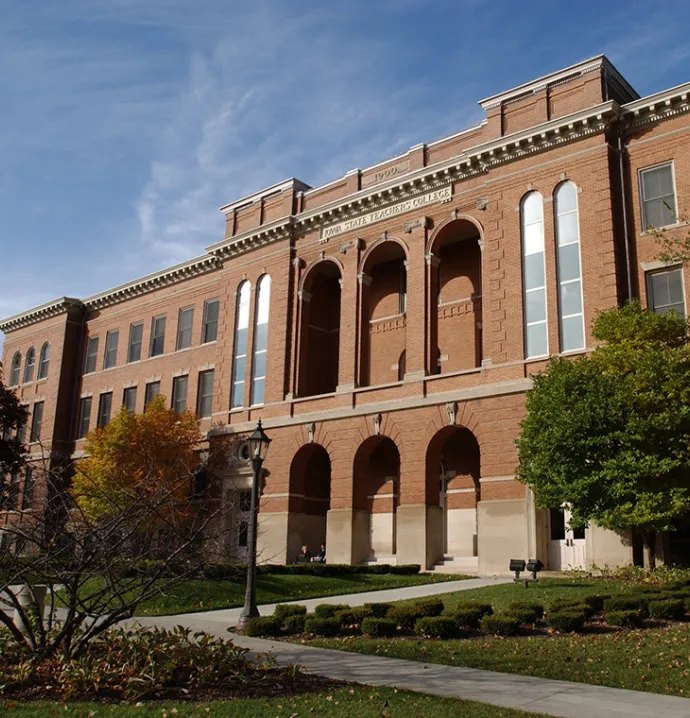The exterior of a brick building on a college campus displays magnificent architecture, such as arches and large windows