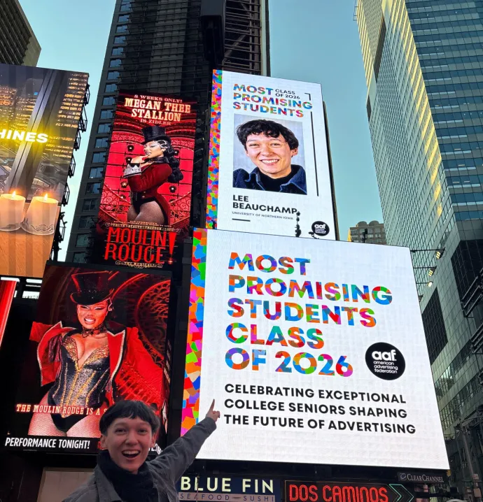 Lee Beauchamp pointing to a billboard of themselves in Times Square