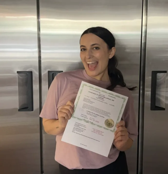 UNI graduate, Maddie Palmersheim, holds passed inspection certificate on her new location on College Hill.