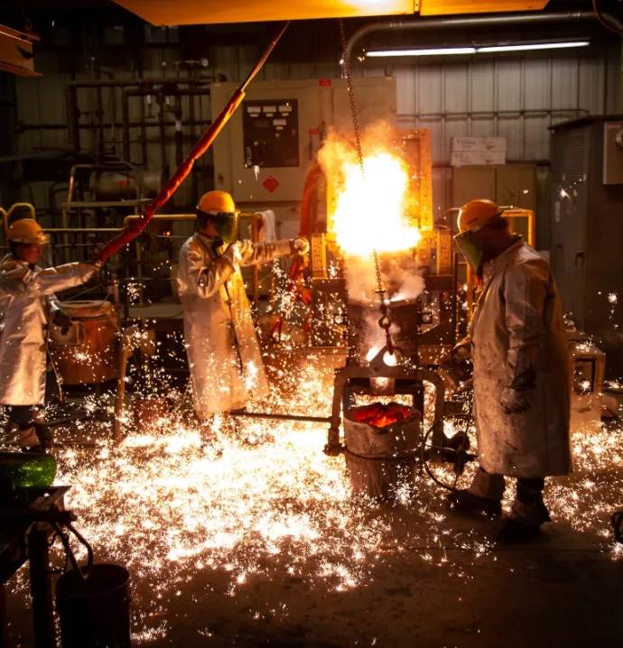 People in protective gear casting metal