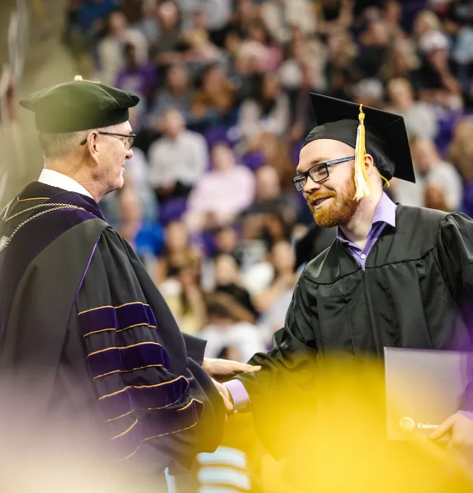 Student shakes hands with President Nook at Commencement