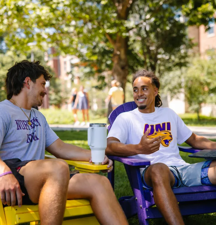 Students sitting in Adirondack chairs on UNI campus