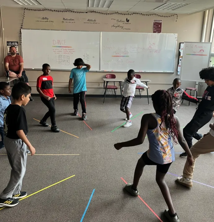 Students playing a dance game on colored lines on the carpet