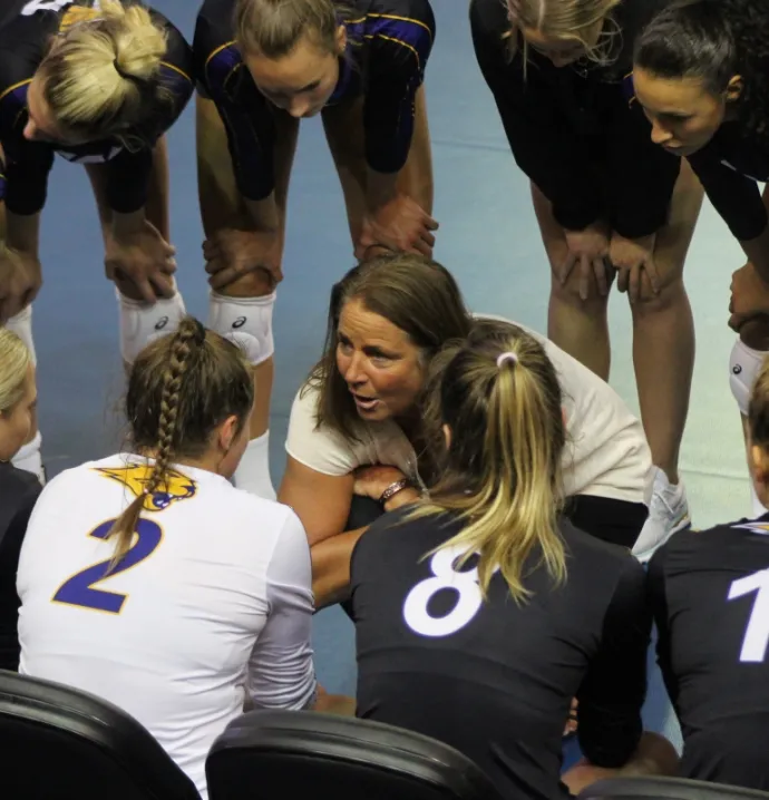 Bobbi Petersen talking to volleyball players in a huddle