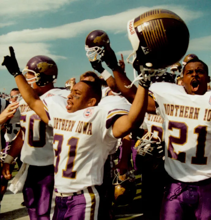 1994 UNI Football players cheering with helmets raised in the air