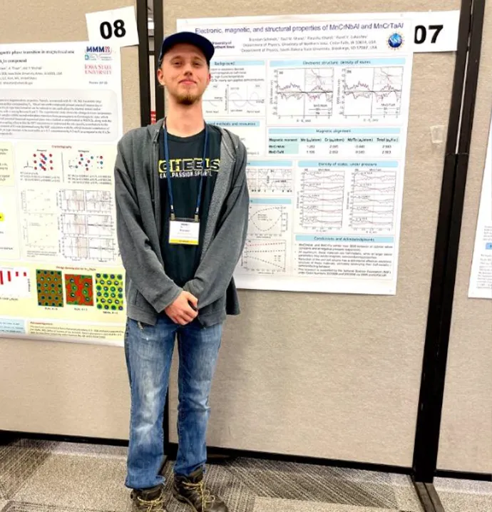 Student standing front of his work at conference
