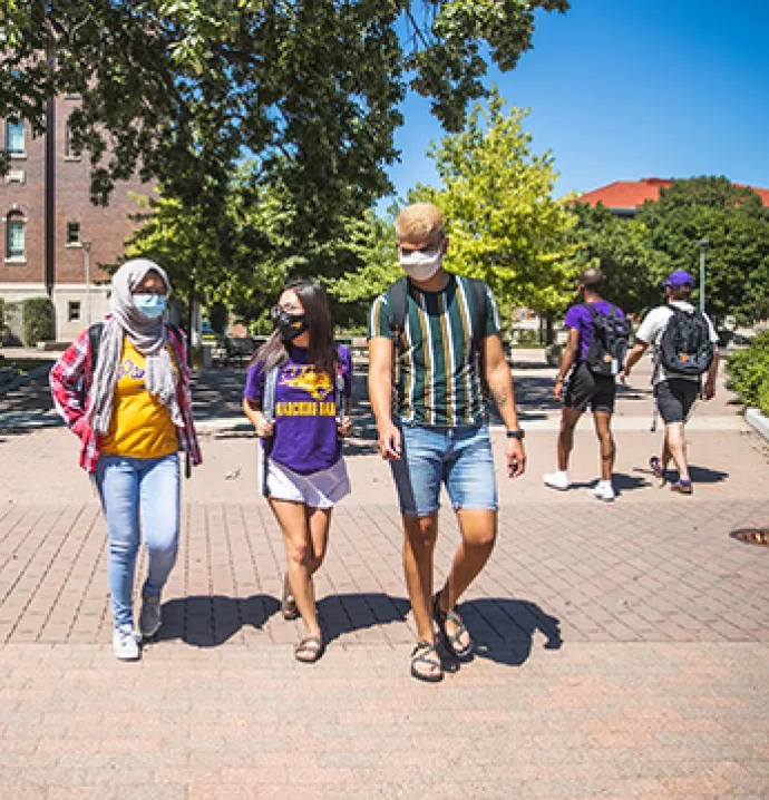 Masked UNI students walk on campus.