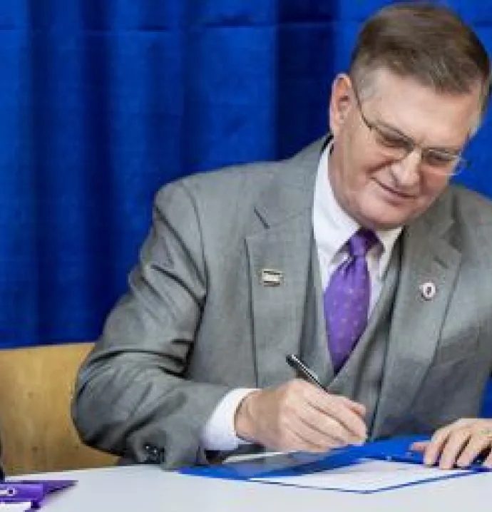 UNI President Mark A. Nook signs an agreement with DMACC.