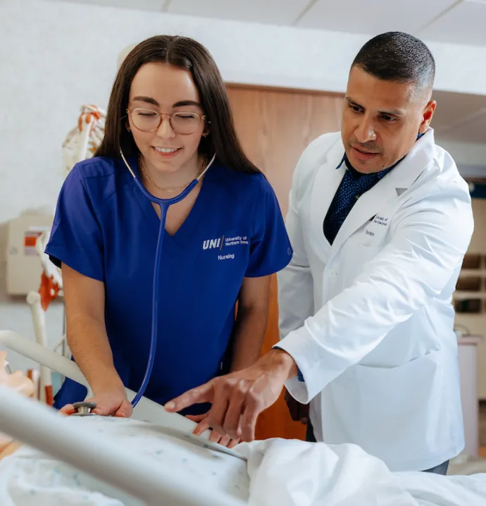 Jimmy Reyes helps student examine simulated patient