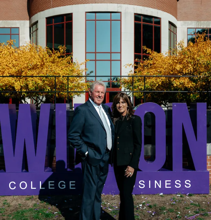 David and Holly Wilson standing in front of Wilson College of Business sign