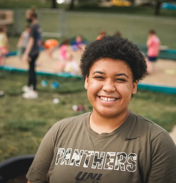 Teacher education student standing in front of children playing in a sandbox