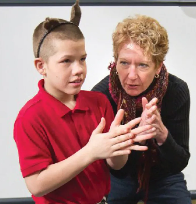 Gretta Berghammer works with a child to place hands together