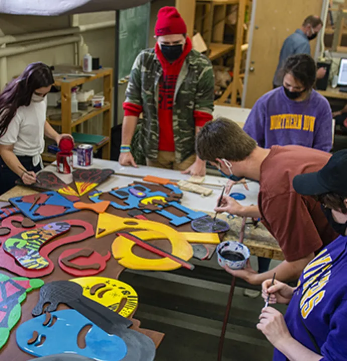 UNI art education students work on a piece of art they helped create with students from Holmes Junior High.