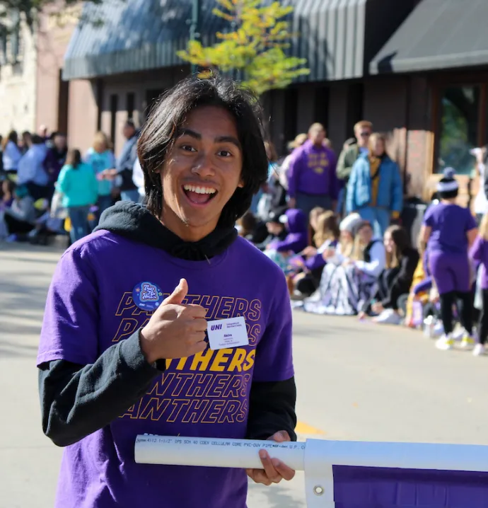 Student giving a thumbs up as they march in UNI Homecoming Parade