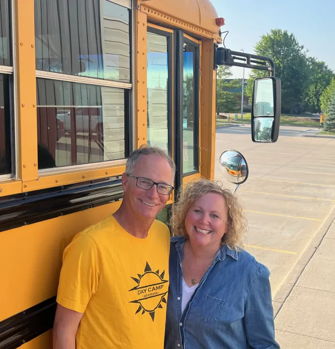 Adam and Darcy Nidey standing in front of a school bus