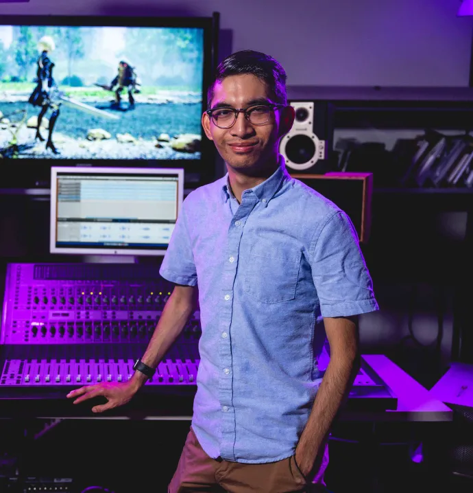 Man standing next to sound table setup with video screens in background