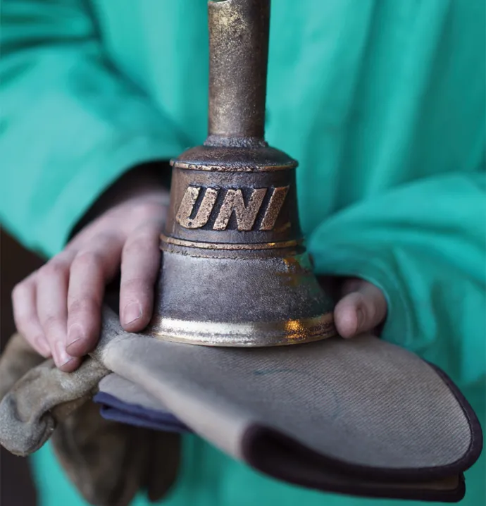 Student holds a newly caset bell that says "UNI" on the side