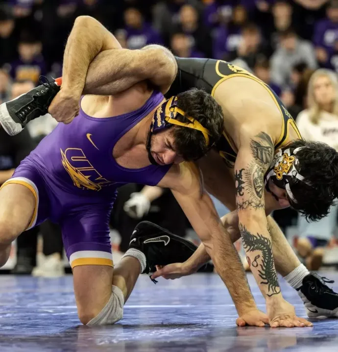 UNI student-athlete Julian Farber drives through a takedown during a wrestling match