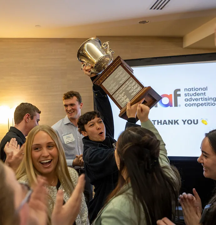 Students cheer as they raise up trophy.