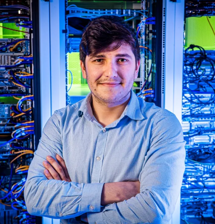 Student standing in front of computer system with arms crossed